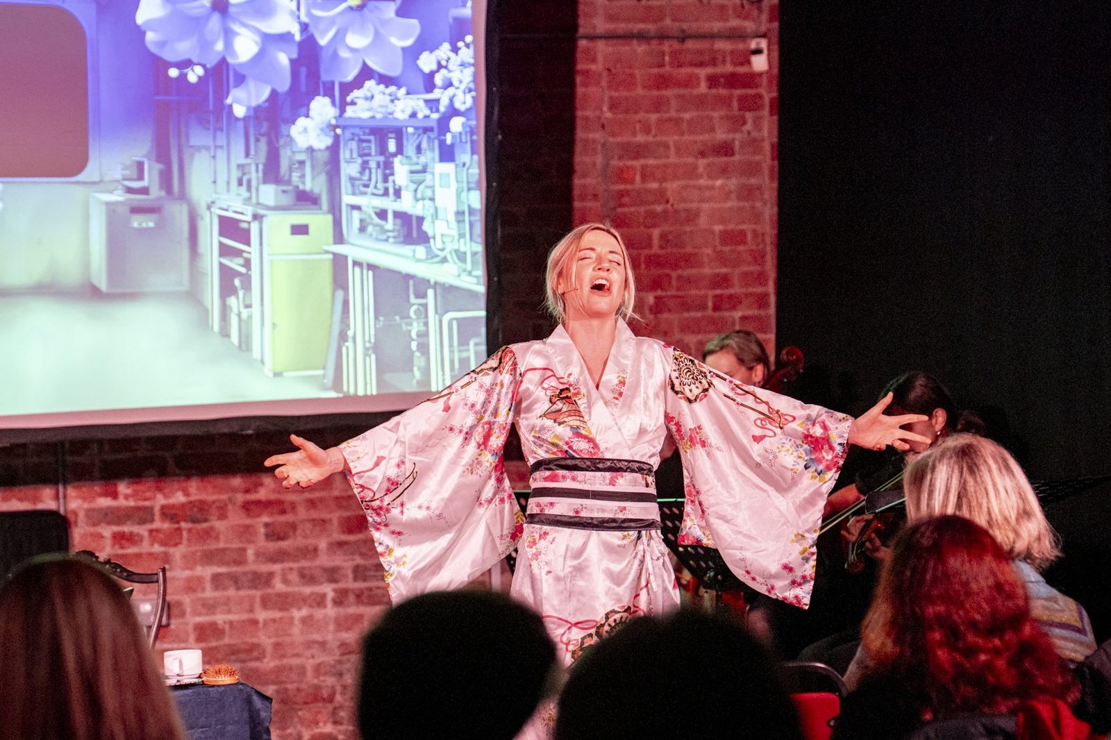A singer in a kimono, arm outstretched, in performance